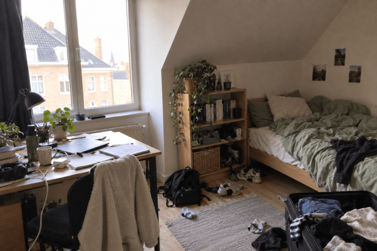 Illustration of a messy Belgian student room with an unmade bed, open suitcase and notes on the desk